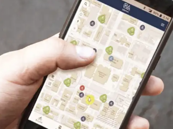 ɫӰ student holding a phone navigating an interactive map