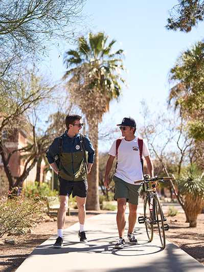 Two students walking by old main